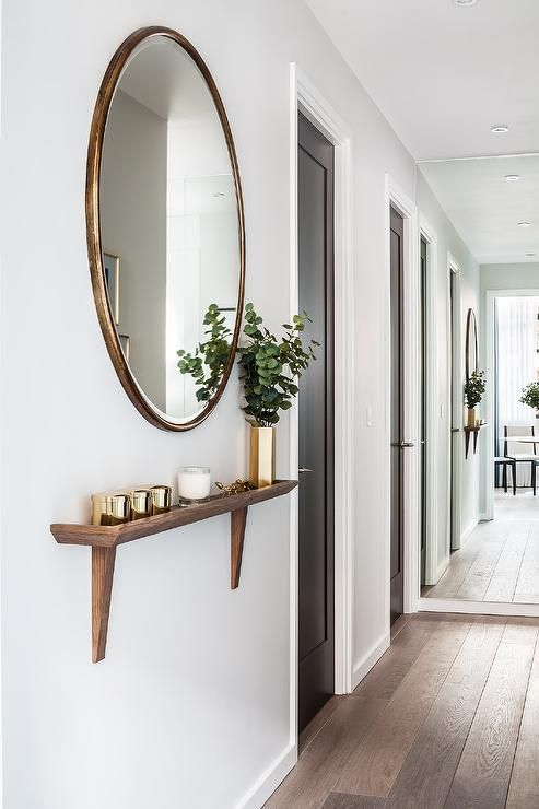 Chic foyer hallway features a round gold oversized mirror placed