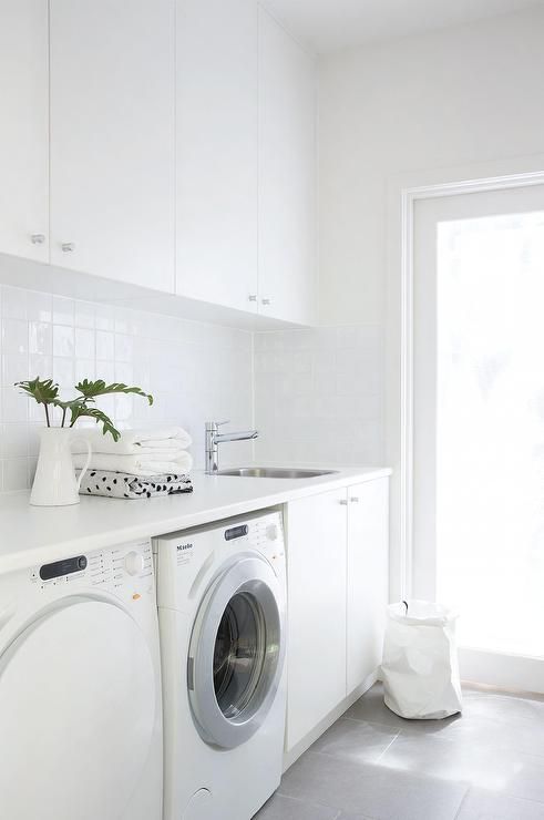Modern white laundry room features white cabinets paired with white