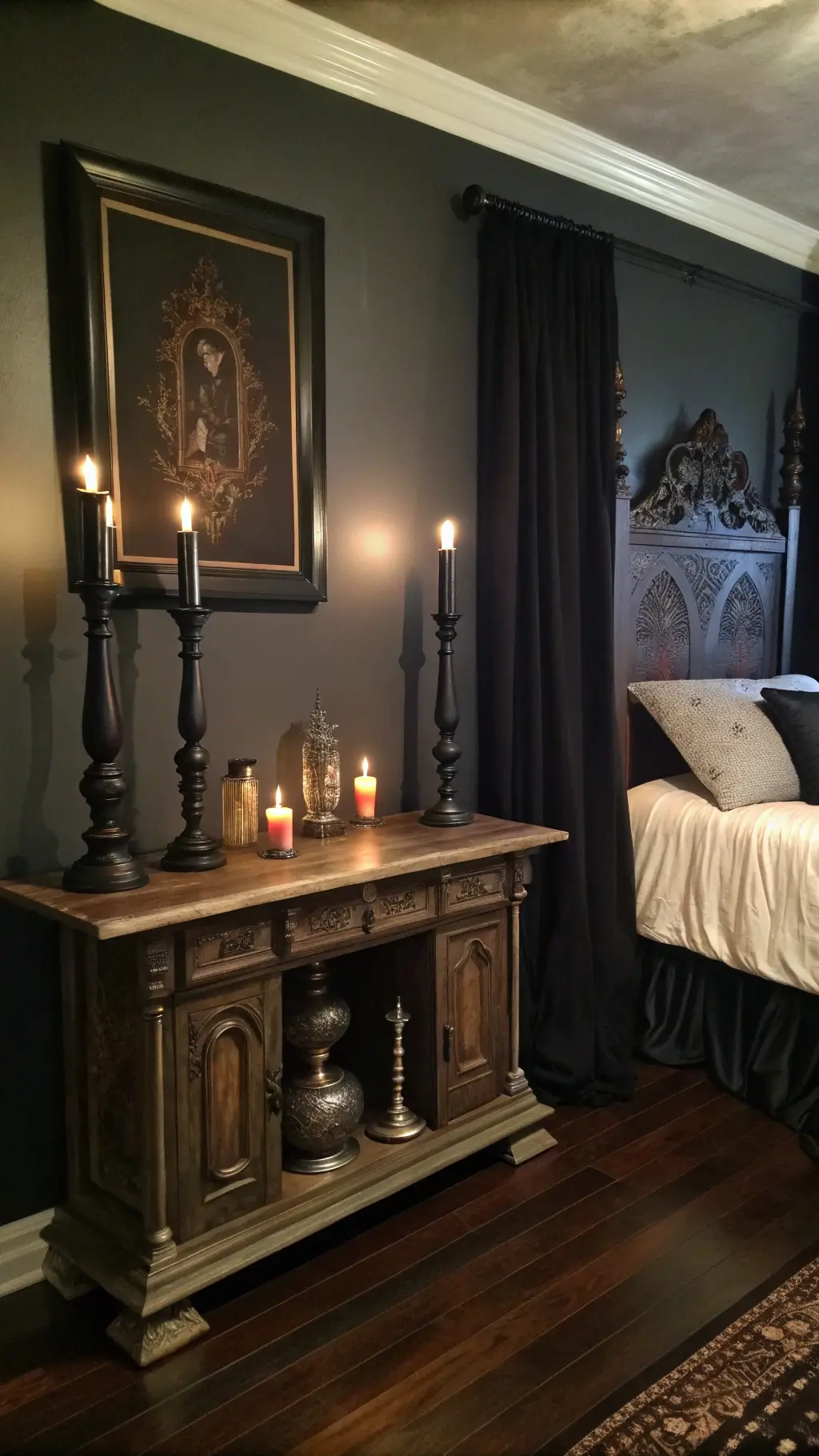 Gothic bedroom with antique altar table as headboard, black candles, mercury glass decor, heavy silk drapes, dark hardwood floors, and asymmetrical artwork on charcoal walls.