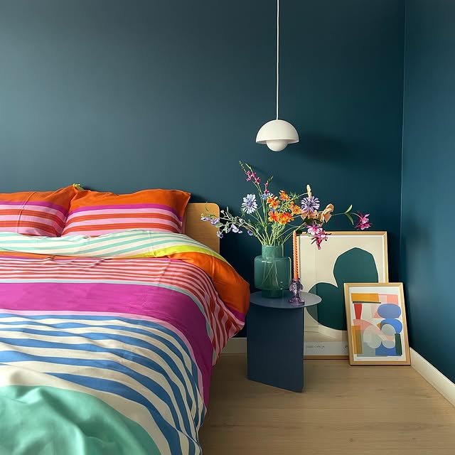 Dark blue-green bedroom with colorful bedding